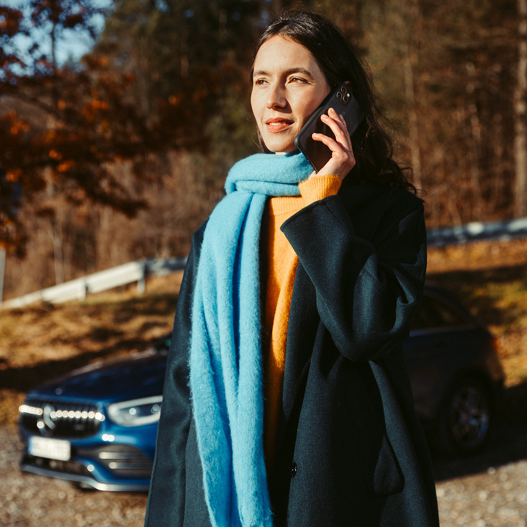 Asistencia en carretera | Mercedes-Benz Una mujer habla por teléfono delante de su Mercedes SUV.