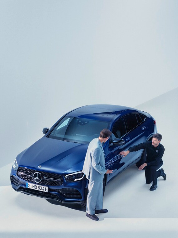 Hombre del equipo de apoyo de Mercedes-Benz arrodillado junto a un Mercedes-Benz averiado