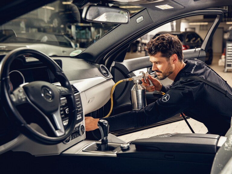 Un técnico de Mercedes-Benz limpiando el aire acondicionado.