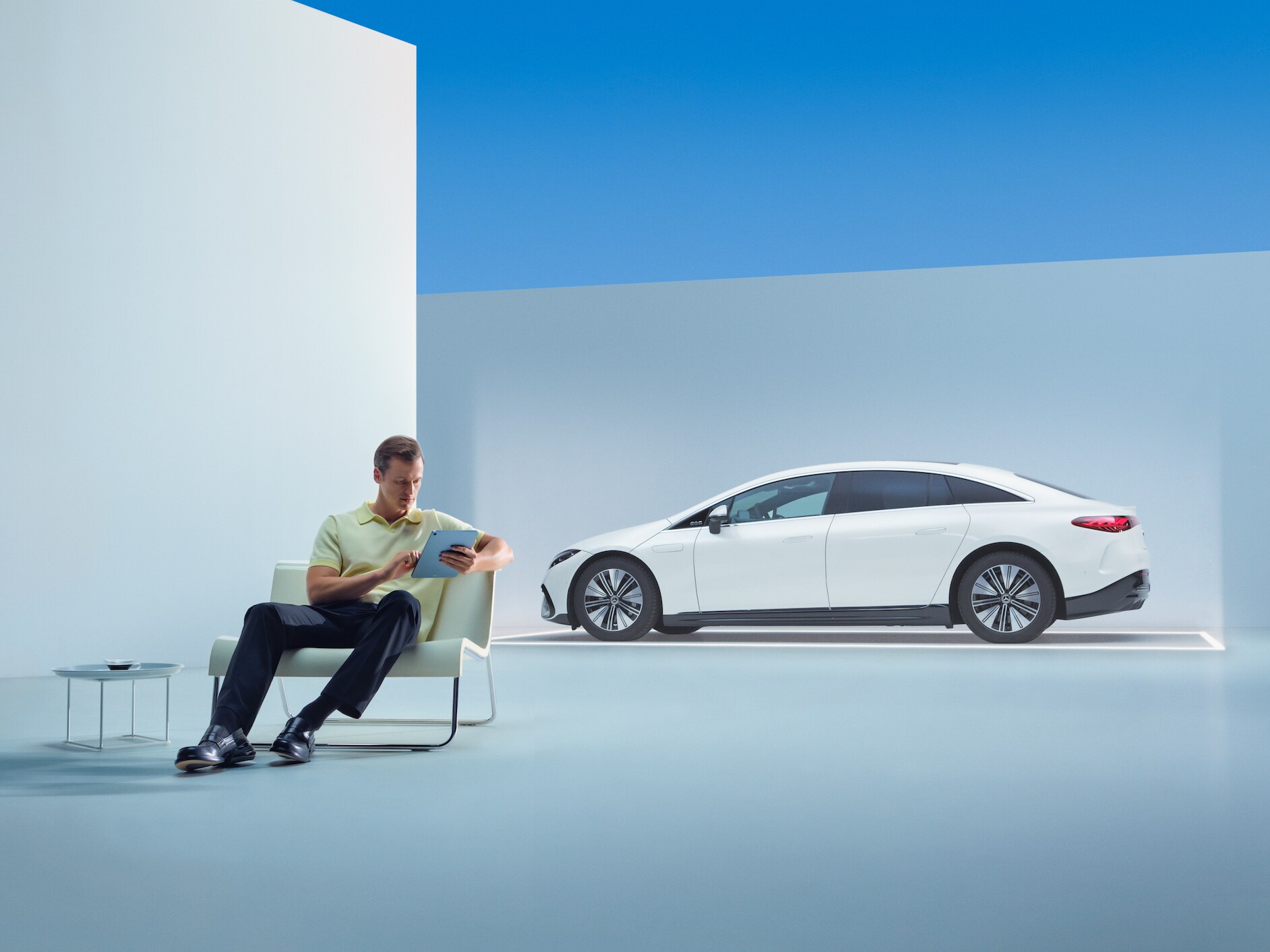 Un hombre relajado sentado con su tableta delante de su Mercedes.